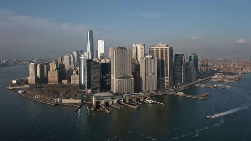 Aerial view of Lower Manhattan skyscrapers Battery Park and the East River in New York City during winter as a boat leaves a wake in the water