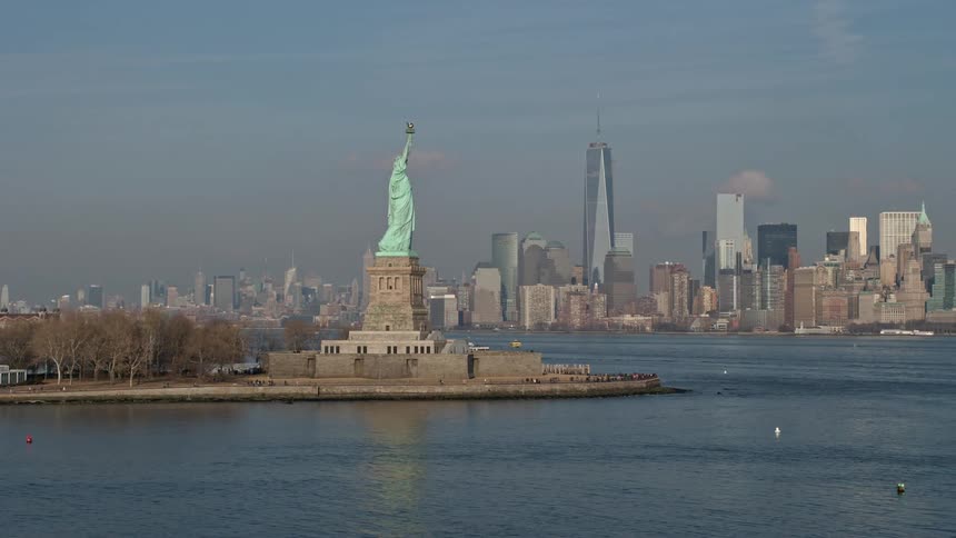 Aerial flyby of the Statue of Liberty towards the Freedom Tower and Lower Manhattan skyline in New York City during winter