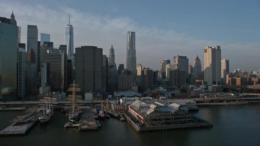 Aerial footage reveals Lower Manhattan skyline piers and historic ships along the waterfront during winter in New York City