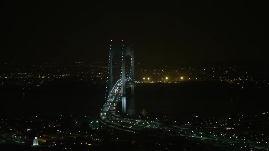 A night-time aerial passing of the Verrazano-Narrows Bridge in New York City during winter