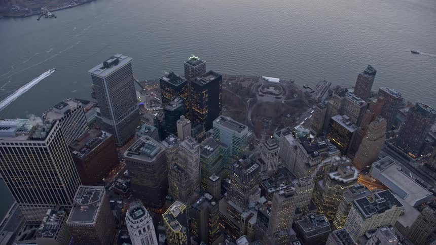 A birds eye view of downtown skyscrapers and Battery Park with cloudy skies and a wintertide in Lower Manhattan during twilight