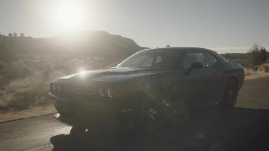 A modern muscle car speeds down a highway in the desert