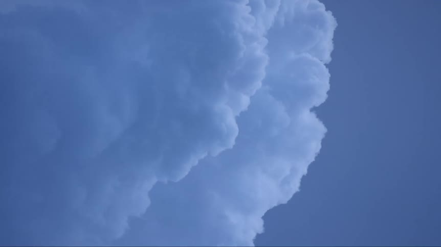 Cumulus clouds move across a blue sky