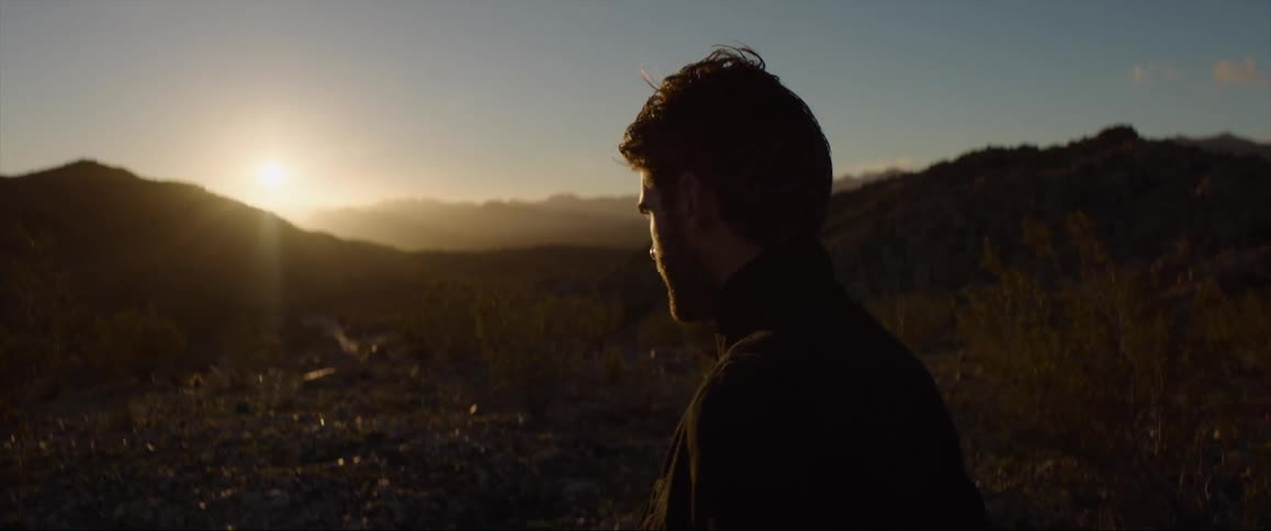 A man is standing outdoors while the sun is setting