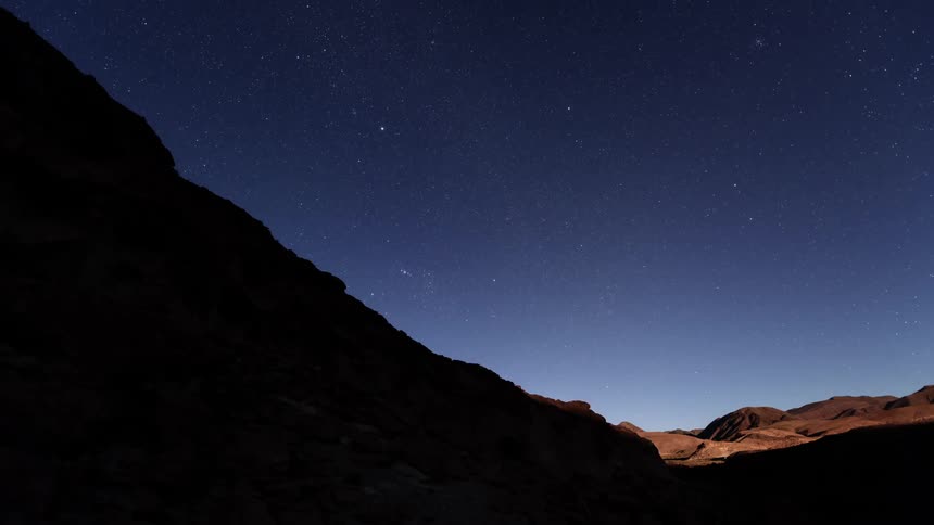 The sun rising over a rocky hillside in nature