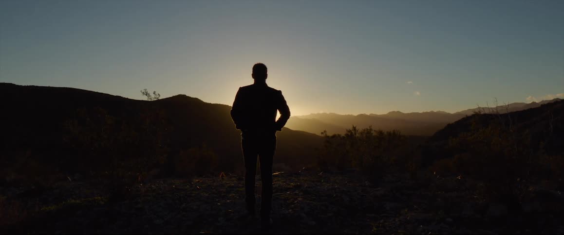 A man is walking outdoors during sunset