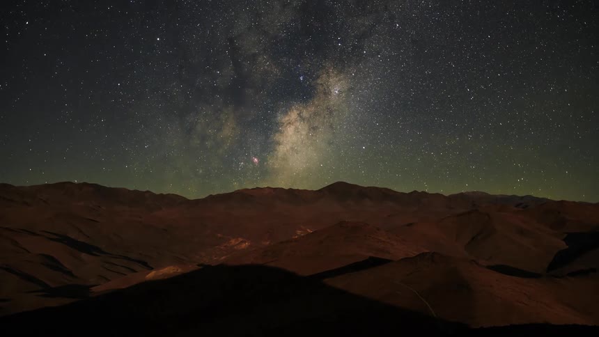 The stars of the milky way move over the mountains as the sky grows darker