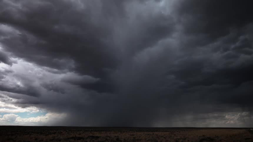 Dark storm clouds floating over a field during a rainstorm