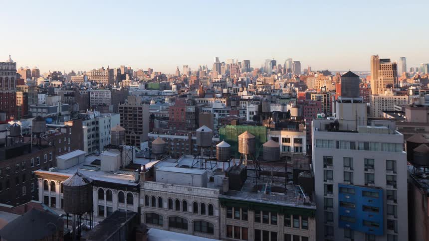 Sunlight and shadow pass over apartment buildings with city skyline in the distance