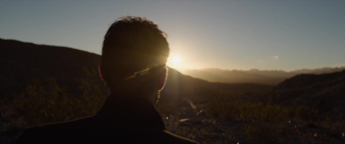 Silhouette of the head of a man walking towards sunset in the mountains