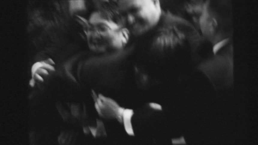 Friends wearing suits extend their hands to catch a friend caught on vintage black and white film