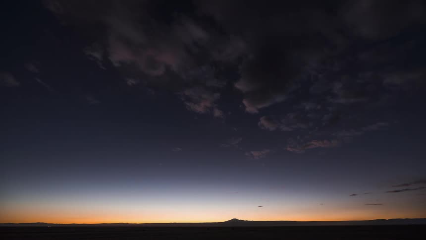 Clouds move across the sky as the sun has set on the horizon