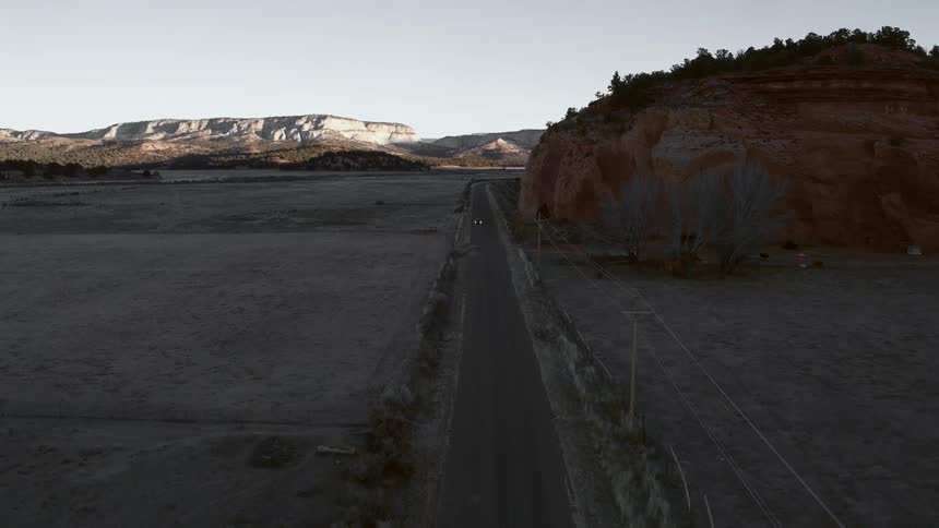 A car drives down a shaded road