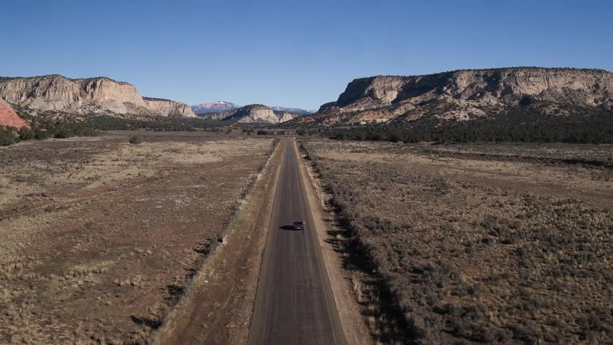 A car drives down a desert road