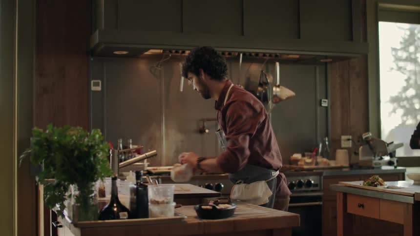A man walks around his kitchen while cooking