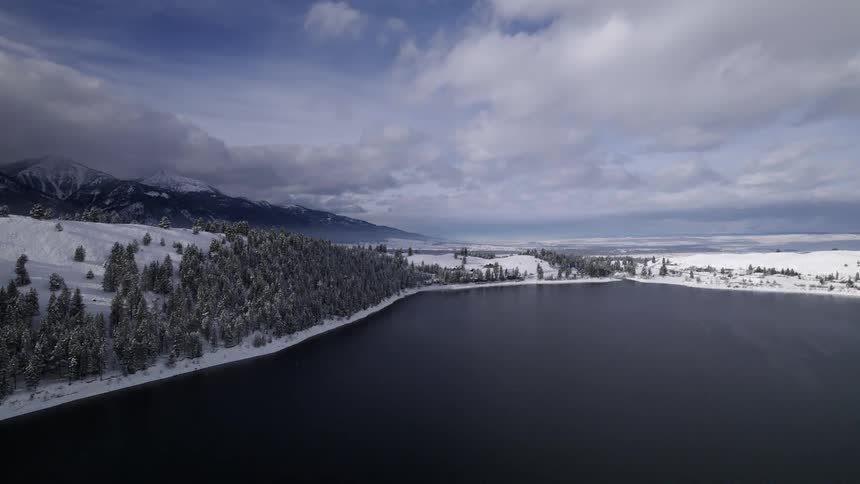 Snow covers the land along a river and below a mountain