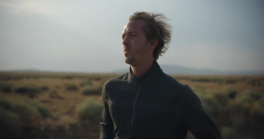 A man is jogging outdoors in a grassland area