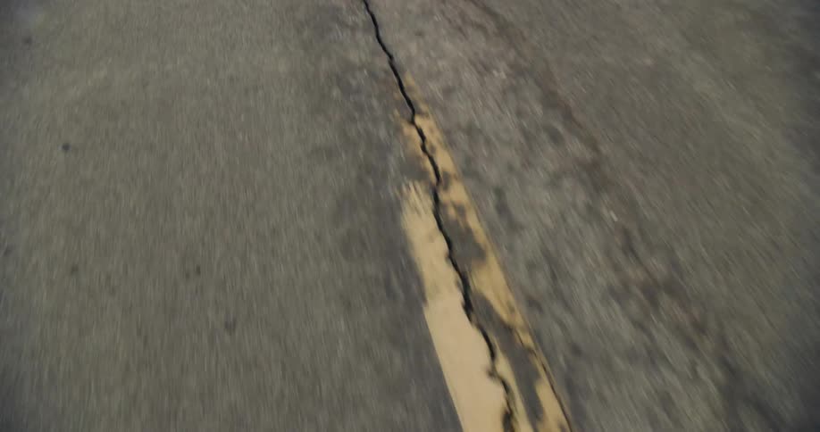 Close up of the cracks and seams on the asphalt of a rural road in bad condition at daytime