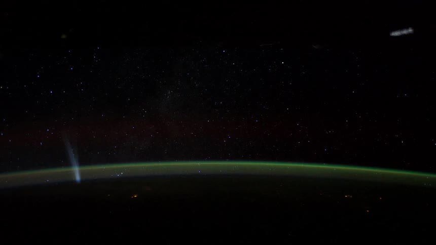 A satellite flies over the earth as it turns in space among the stars