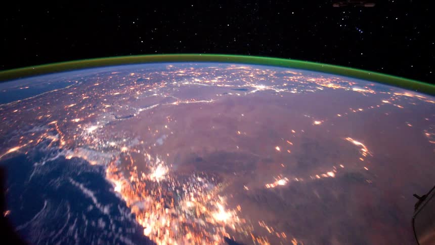 A satellite flies over the earth as it turns in space among the stars