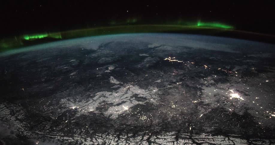 The aurora borealis glows around the earth as it rotates in space