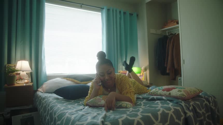 Woman laying on a bed talking on the phone