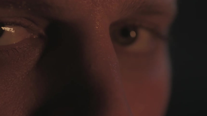 A man looks pensive at night with a flickering light illuminating his face