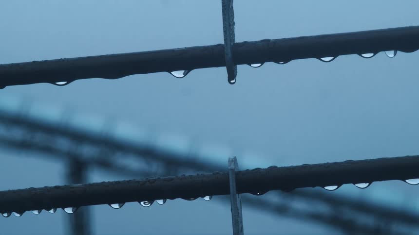 Water droplets hanging from metal poles during a storm