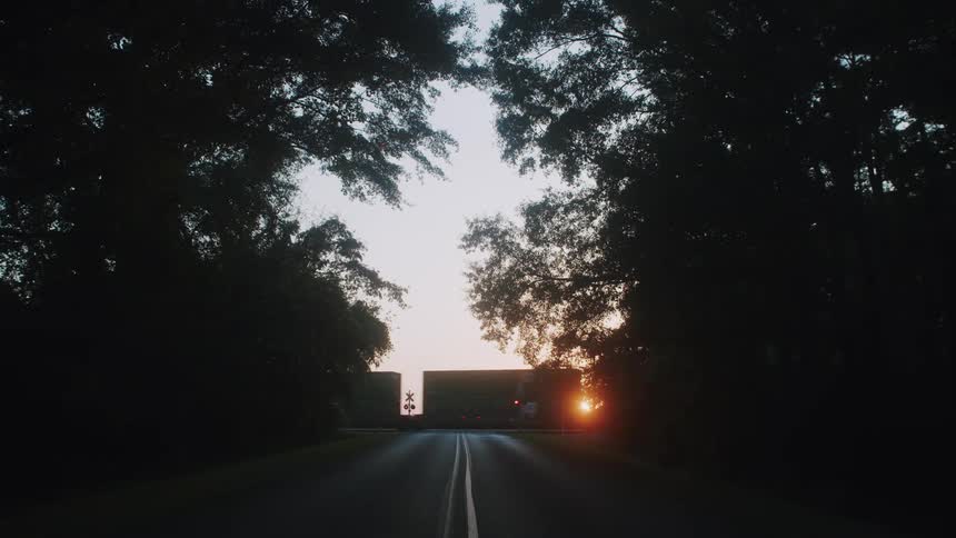 A train is moving through a rural area at dusk