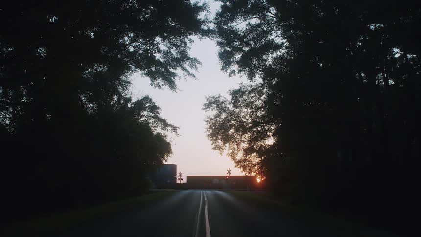 A train is moving in a rural area during sunset