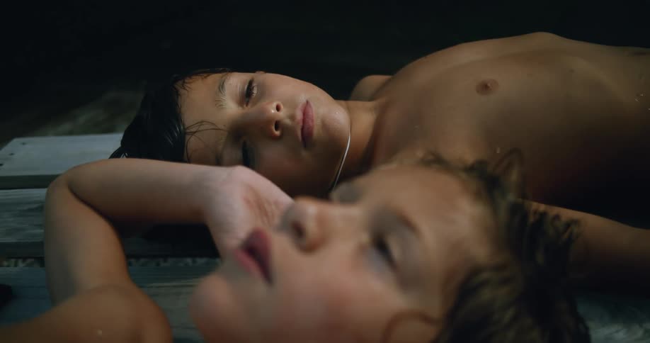 Two young kids are laying down on some wood and listening to music