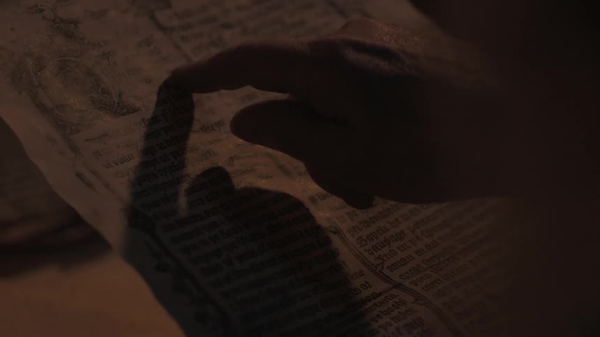 A person is pointing at words on a page