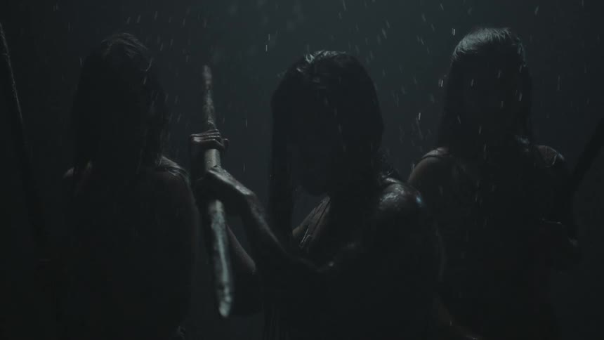 Three women warriors stand in fighting stances on a rainy night