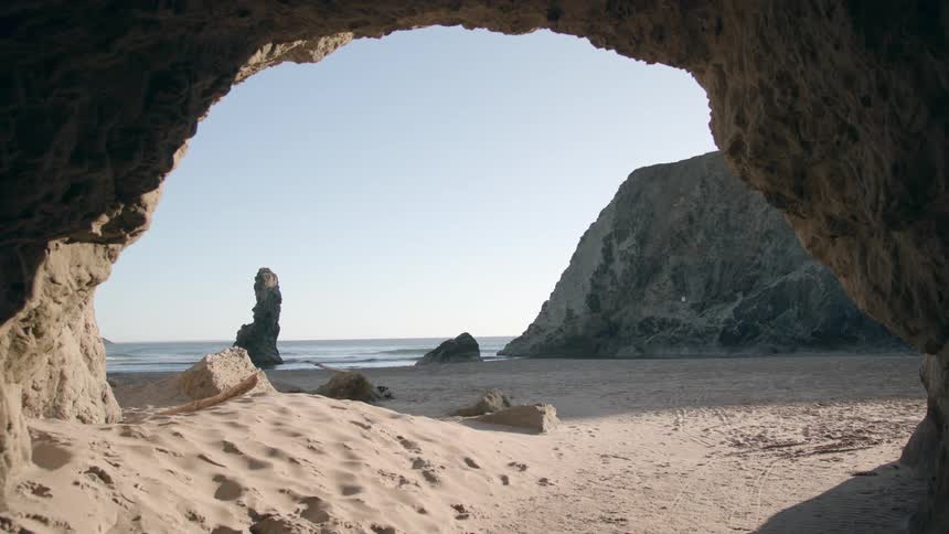 A cavern on a sandy beach during the day