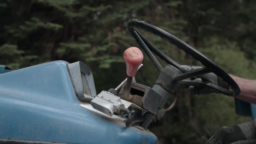 A man shifts and gear and starts a tractor