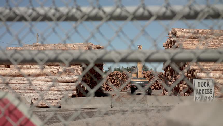 A tractor is picking up lumber at a dock