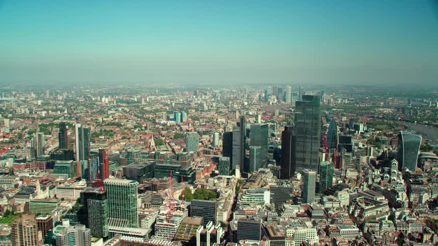 Construction cranes work on buildings near football field and downtown skyscrapers on hazy day