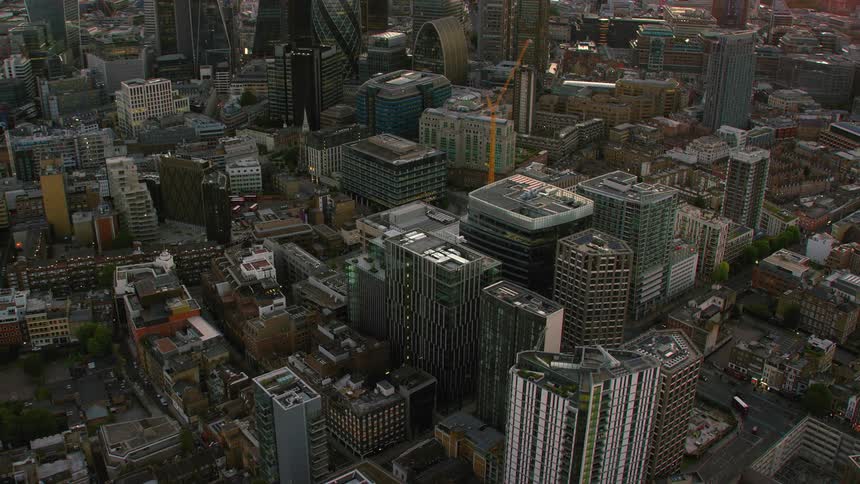 Aerial view of a dense city with tall buildings and an orange and pink sunset