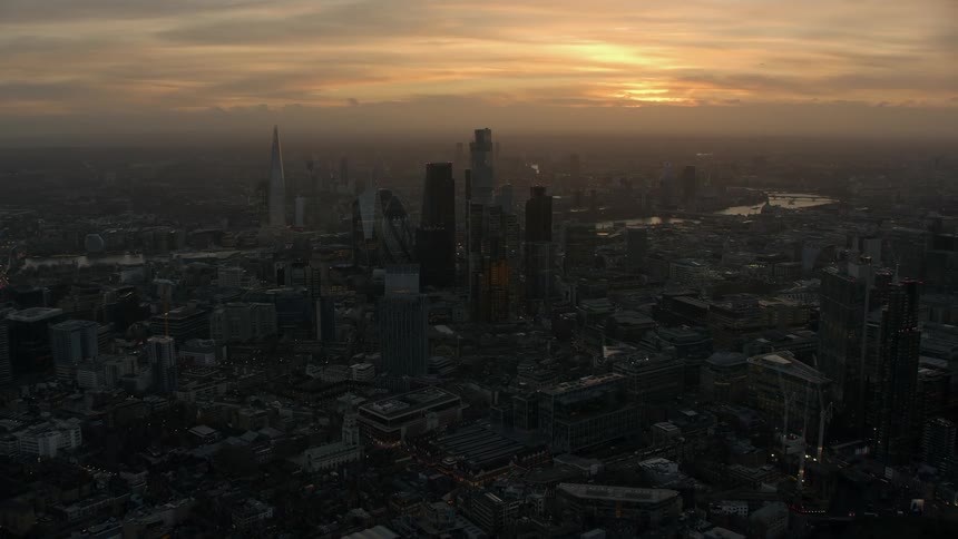 Skyscrapers loom over the surrounding buildings in a metropolis at sunset