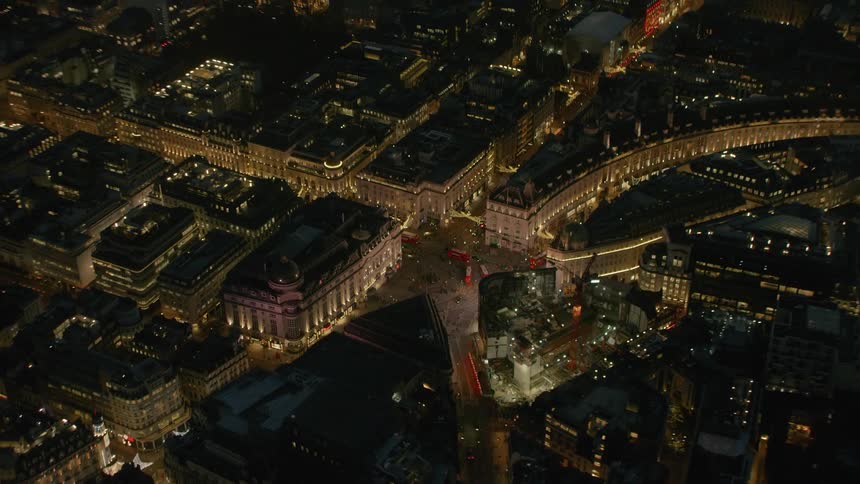 An aerial view of a city that starts close and gets further away of large buildings and streets that weave throughout them
