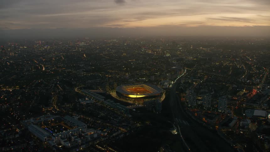 Aerial view of illuminated city skyline and football stadium at dusk in london