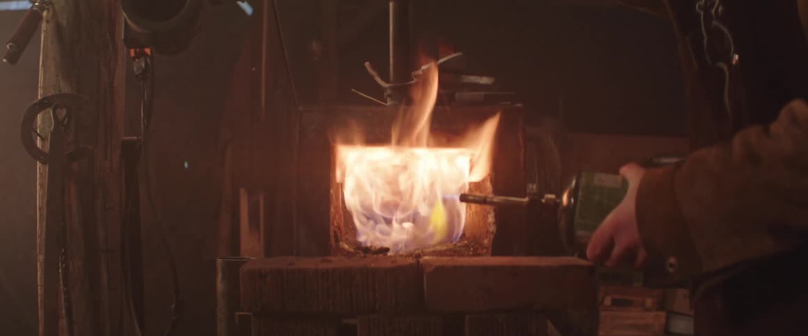 Blacksmith uses a propane torch to light a forge in his workshop