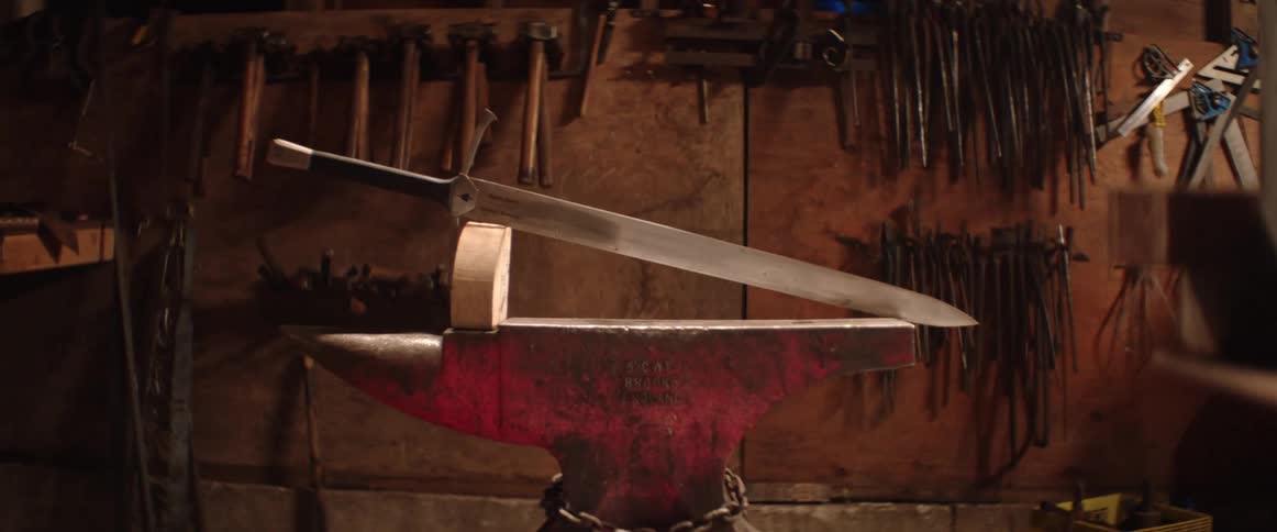 A sword on a wooden display sitting on an anvil