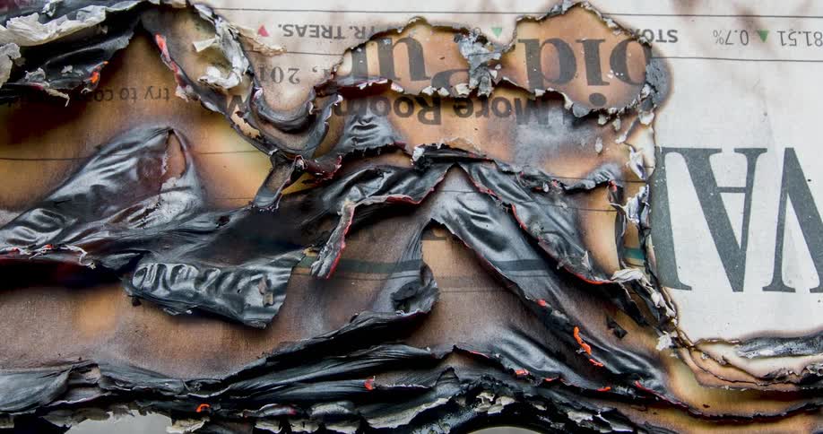 Flames rise from a burning newspaper