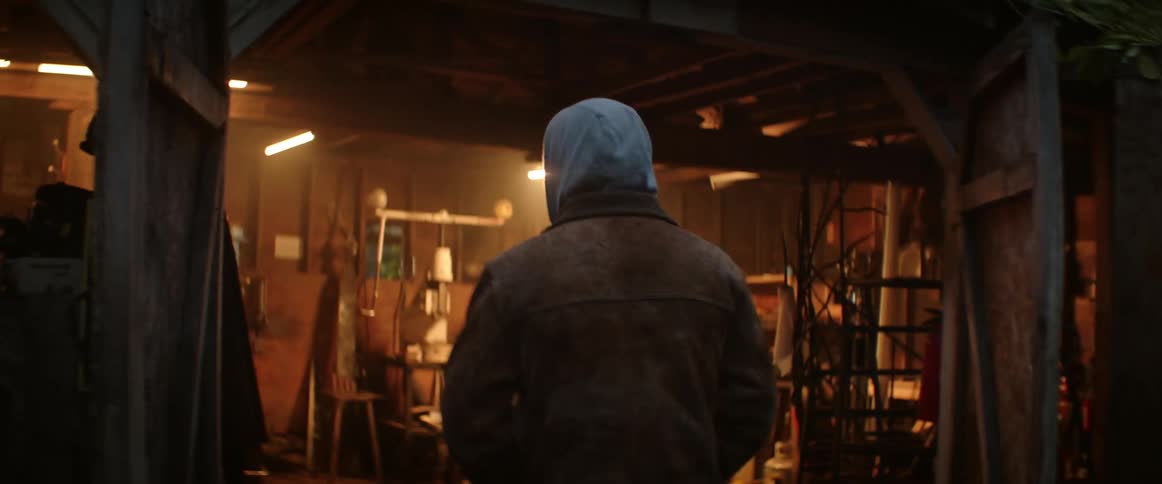 A man gets out of his truck and walks over to a workshop where he puts on a blacksmith apron