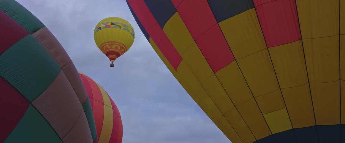 Hot air balloons close together and one up in the sky
