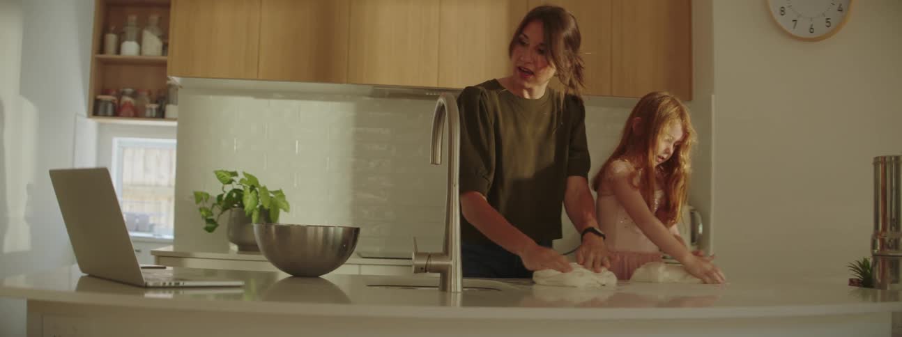 Mother and daughter kneading dough in the kitchen countertop at home