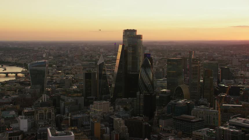 Skyscrapers loom over a metropolis at sunset