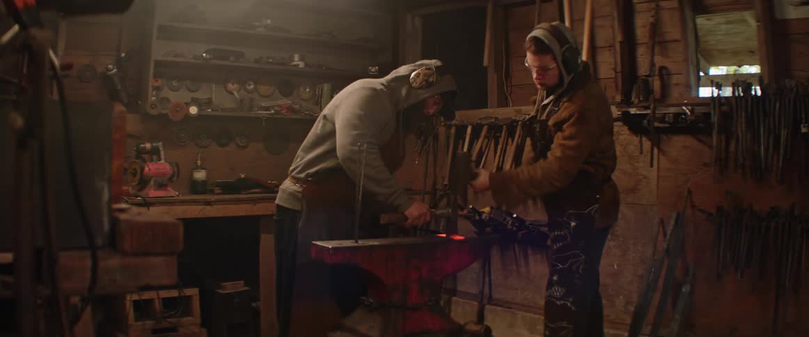 Blacksmith shapes metal by heating it in a fire and hitting it with a hammer