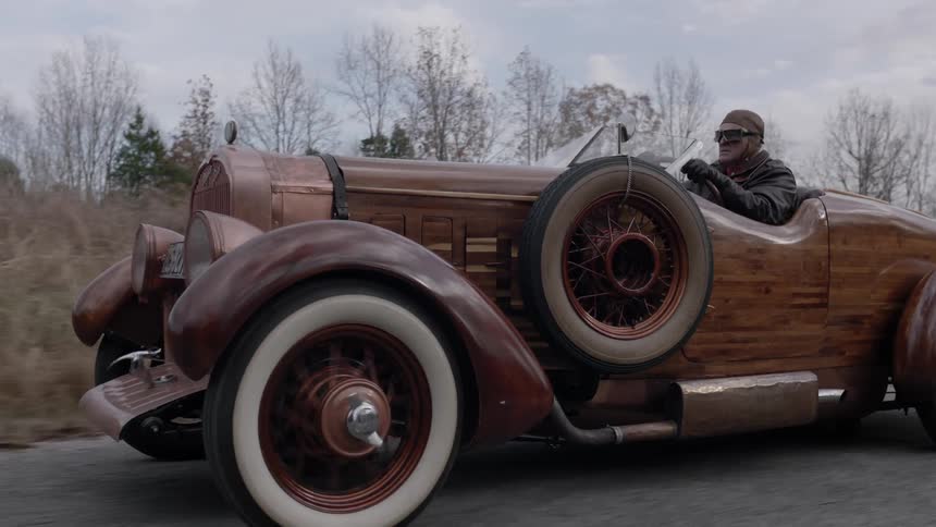 An antique car is driven on a rural road